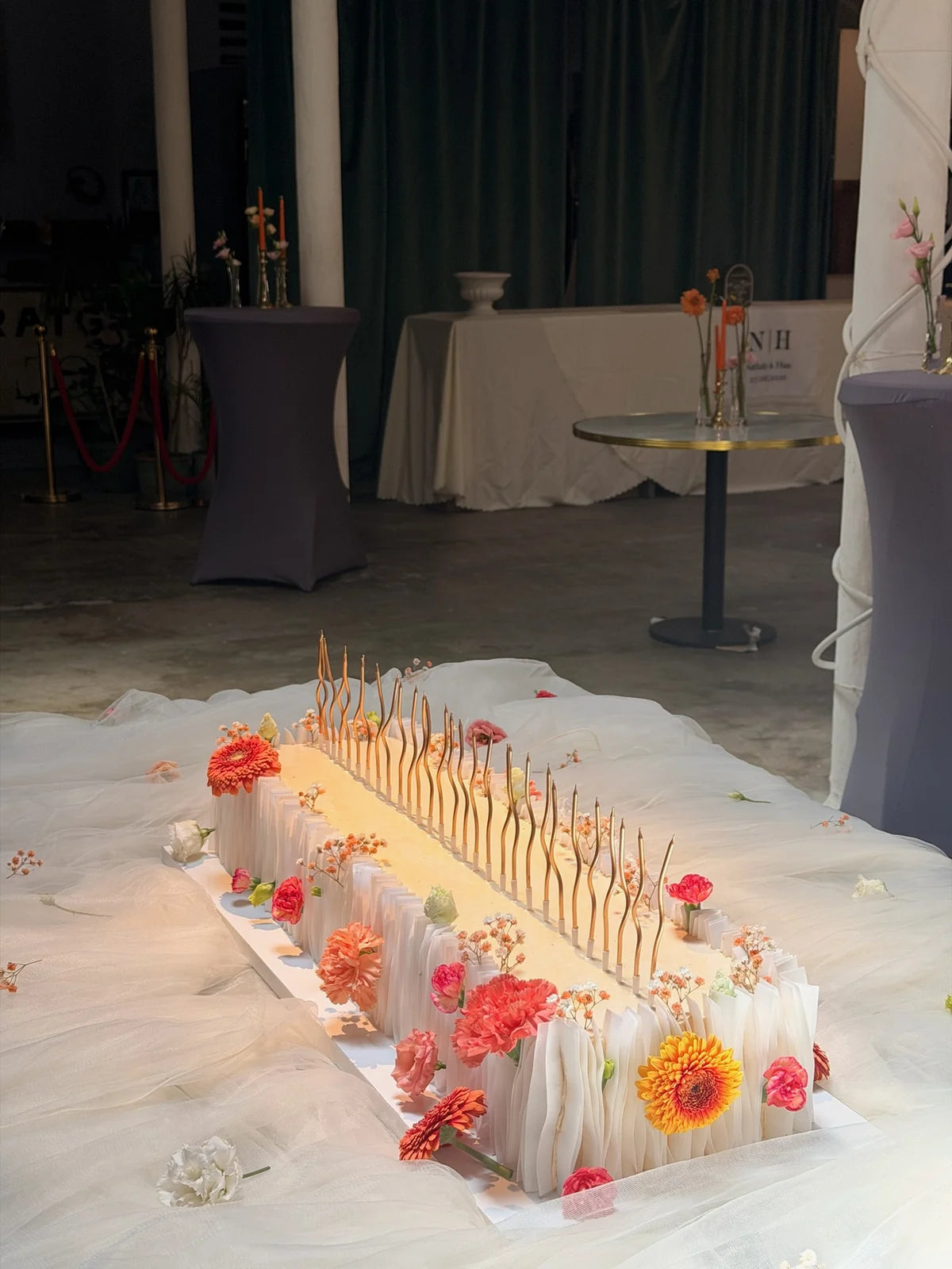 Tarta larga para evento decorada con flores y velas